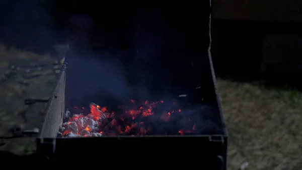 Mann legt rohes Fleisch auf einen heißen Grill, um es mit einer Holzzange zu grillen, Nahsicht über einen dunklen Hintergrund. Dinner Party, Barbecue und Schweinebraten am Abend. Grillhintergrund — Stockfoto