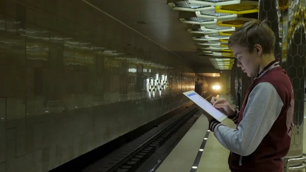 Człowiek za pomocą płytki dotykowej lub smartfona, gdy czeka na pociąg na stacji metra. Biznesmen przy użyciu komputera Wireless Digital Tablet Pc w pociągu, kolejowe lub stacji metra w nowoczesnego miasta — Zdjęcie stockowe