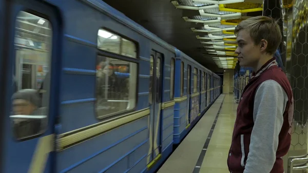 Mies käyttää kosketuslevyä tai älypuhelinta odottaessaan junaa metroasemalla. Liikemies, joka käyttää langatonta digitaalista Tablet PC-tietokonetta rautatie-, rautatie- tai metroasemalla Modernissa kaupungissa — kuvapankkivalokuva