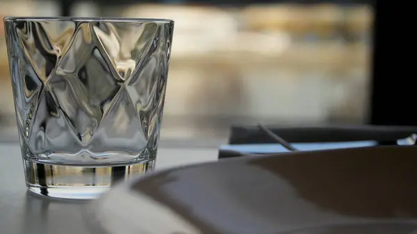 Facettiertes Glas Wasser auf Naturhintergrund. Klares facettiertes Glas mit Whiskey auf einem dunklen Holztisch, Nahaufnahme. leeres facettiertes Glas — Stockfoto