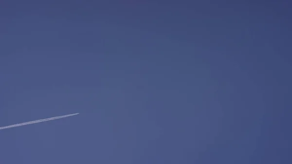 Grand avion supersonique de passagers volant haut dans un ciel bleu clair, laissant une longue traînée blanche. Avion volant dans des nuages blancs dans un ciel bleu. Avion volant ciel bleu — Photo