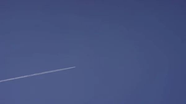 Grand avion supersonique de passagers volant haut dans un ciel bleu clair, laissant une longue traînée blanche. Avion volant dans des nuages blancs dans un ciel bleu. Avion volant ciel bleu — Photo