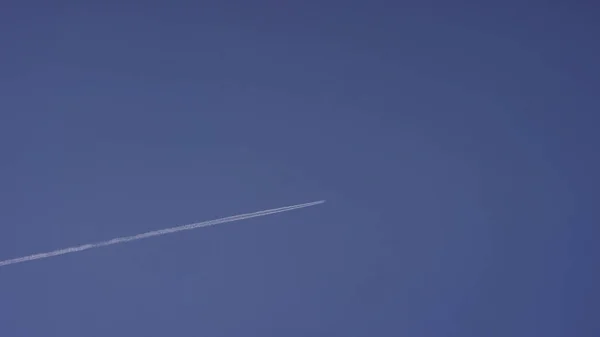 Grande aereo supersonico passeggero che vola alto nel cielo blu chiaro, lasciando lunghe tracce bianche. Aereo che vola in nuvole bianche in un cielo blu. Aereo che vola cielo blu — Foto Stock