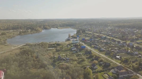 Légifelvételek az Európai falu közelében a tó. A szín-tó és a falu, a templom gyönyörű légifelvételek. Felülnézete a falu és a tó — Stock Fotó