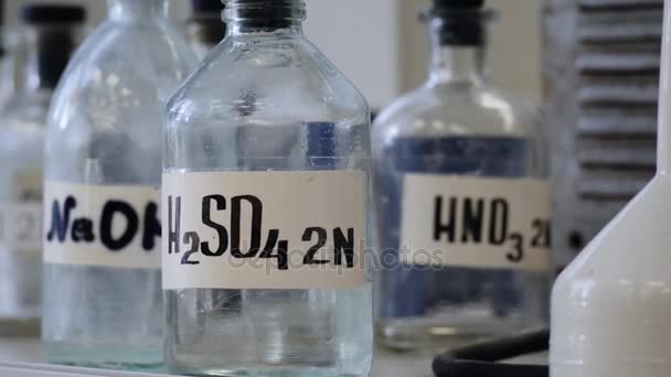 Бутылки растворов, хранящихся на полке в лаборатории. Бутылки с химическими растворами NaOH, H2so4 и HNO3. Серная кислота, гидроксид натрия, азотная кислота — стоковое видео