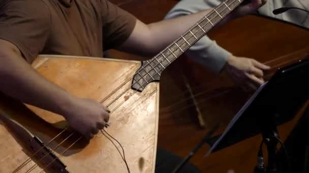 Balalaika di legno nelle mani del musicista. Arte musicale popolare della tradizione rurale. L'uomo interpreta il contrabbasso Balalaika — Video Stock