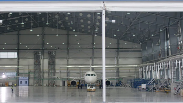 Roller shutter door and concrete floor of airport hangar and airplane background. Airport hangar from the outside with big tall doors. Front view. Aircraft Hangar — Stock Photo, Image