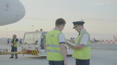 Yekaterinburg, Rusya - Ağustos 2017: iki havayolu pilotları, uçuş için hazırlık planı, seyir defteri denetimi kağıtları uçuş. Profesyonel okuma pilotlar ve yatılı kapısında onların uçuş belgelerin hazırlanması