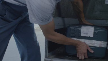 Adam bir bavul bagajdan çeker. Erkek işçi bagajdan seyahat için uçak kullanan bir işadamı Bagaj alır.