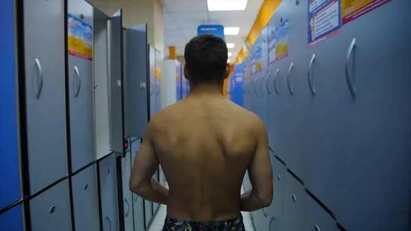 年轻的运动员在走廊对封闭的储物柜在游泳池连续。更衣室里一个人的后景 — 图库照片