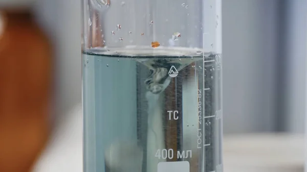 Fluid changes color after mixing. Close-up of colorful flask in which the liquid is mixed by a special device