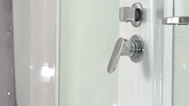 Mano femenina usando grifo de baño en cabina de ducha. Primer plano de un regulador de perillas de ducha y su dispensador de agua. Grifo del baño. Primer plano de un regulador de botón de ducha y dispensador de agua . — Vídeos de Stock