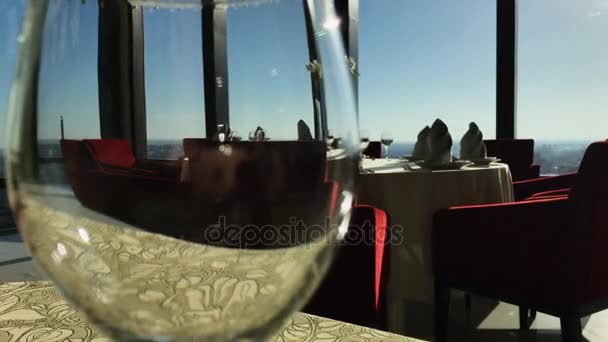 Вид города отражается в бокале вина. Запись. Вид на город из ресторана. Ресторан в небоскребе с видом на город, стакан на переднем плане — стоковое видео