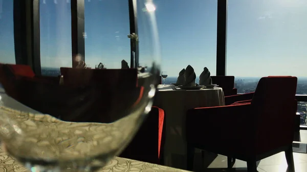 Vista de la ciudad reflejada en la copa de vino. Filmación. Vistas a la ciudad desde el restaurante. Restaurante en un rascacielos con vistas a la ciudad, un vaso en primer plano — Foto de Stock