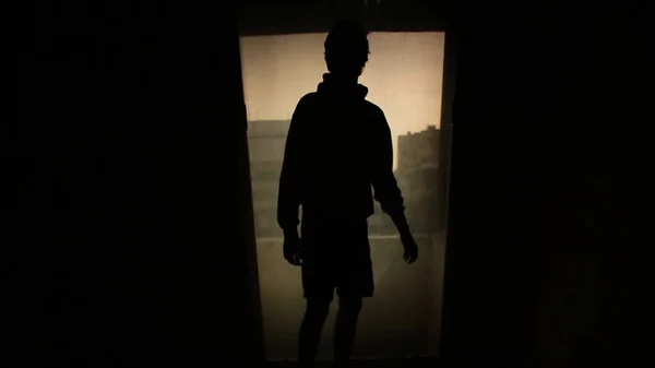 Silhouette man looking out the window with the light in the room. Footage. Silhouette of a young lonely man in the room. Concept of loneliness — Stock Photo, Image