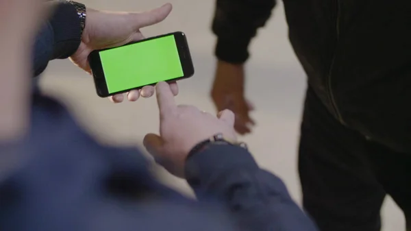 Homme montre à son ami nouvelle application sur son téléphone mobile. Téléphone avec écran vert. L'homme utilise un téléphone avec un écran vert — Photo