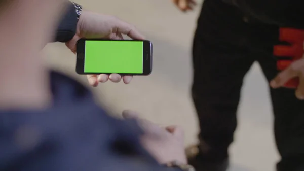 Homme montre à son ami nouvelle application sur son téléphone mobile. Téléphone avec écran vert. L'homme utilise un téléphone avec un écran vert — Photo