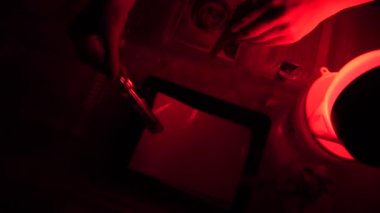 Karanlık oda yazdırma işlemi fotoğrafçı fotoğraf üretmek için Büyütücü kullanarak yazdırır. Kırmızı karanlık bir odada çalışan kadın