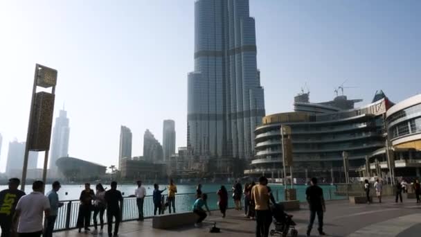 Dubaj, Spojené arabské emiráty - 25 května 2017: lidé chodí na náměstí pozadí věž Burj Khalifa. Věž Burdž Chalífa. Tento mrakodrap je člověkem na světě, měření 828 m. — Stock video