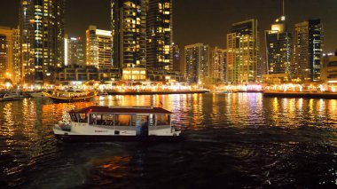 Dubai Marina ve Dubai, BAE Dhow tekne gece aydınlatma. Yapay bir kanal şehri. Motorlu tekne, güzel bir gece şehir manzara arka plan