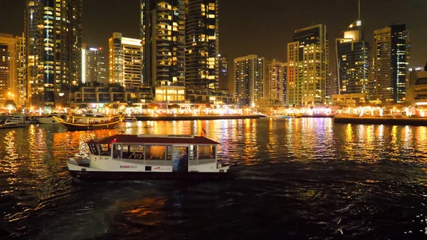 De nachtverlichting van Dubai Marina en de jacht in Dubai, UAE. Het is een kunstmatige grachten stad. Motor boot, mooie nacht stad landschap achtergrond — Stockfoto