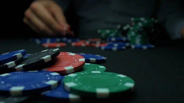 Człowiek rzuca żetony na czarnym tle. Pokerowe żetony Multi kolor z czarnym tłem. Zbliżenie Poker chips w stosy na powierzchni stołu zielonej karty filcu w zwolnionym tempie — Zdjęcie stockowe