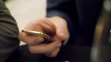 Altın smartphone tutan adam. Altın rengi smartphone eller tarafından sosyal ağlarda güncellenmesi meşgul gerçekleştirildi