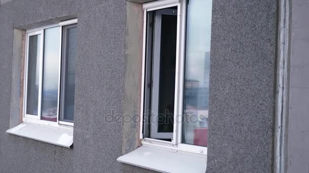 O jovem fuma um cigarro pela janela do apartamento na cozinha. Jovem fuma pela janela do apartamento — Vídeo de Stock