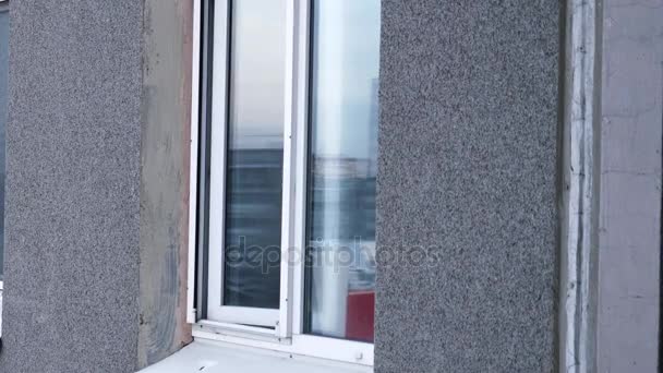 Молодой человек курит сигарету через окно в квартире на кухне. Молодой человек курит из окна квартиры — стоковое видео