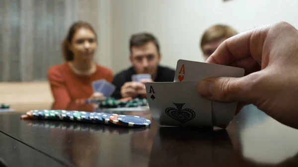 Freizeit, Spiele und Lifestyle-Konzept - glückliche Freunde, die zu Hause Poker spielen. Mann sieht in die Karten und geht die Wette ein — Stockfoto