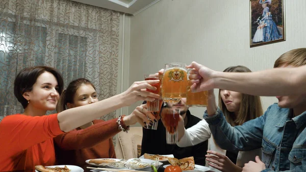 Glückliche Freunde, die sich bei einer Dinnerparty zu Hause amüsieren. Menschen, die Pizza essen, Bier trinken und drinnen Urlaub feiern. Freundschaft, Freizeit, Festkonzept. Freunde kommunizieren zu Hause beim Pizza essen — Stockfoto