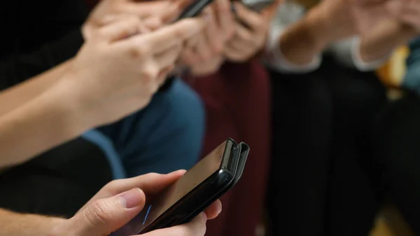 Closeup of friends chatting on mobile phone in network. Group of friends are using gadgets during recreation time at home. Friends sitting and chatting in the phone closeup