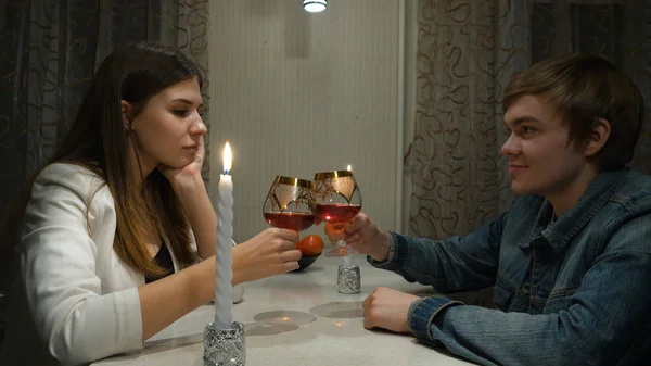 Nuori pari romanttisella illallisella poikaystävänsä kanssa ja juomassa viiniä yhdessä kotona. Tyttö miehen kanssa romanttinen päivä kotona — kuvapankkivalokuva