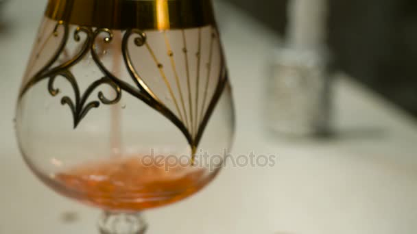 Sklo plné červené víno vylévá z lahve. Nalévání do sklenice na víno červené víno. Víno nalévané do skla closeup — Stock video