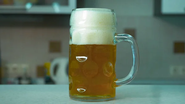 男のクローズ アップは、テーブルからビールのガラスを取ります。男は、テーブルからビールのガラスを取ります。ホーム。男は、台所のテーブルからビールのグラス — ストック写真