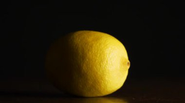 Bir tek taze sarı limon siyah bir arka plan karşı ahşap tahıl masada. Siyah arka planda, closeup taze limon