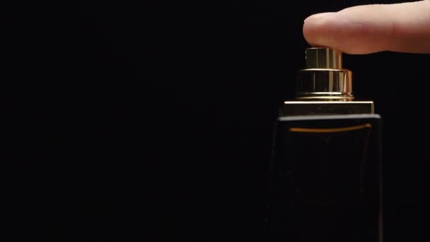 Fragrance luxury bottle contents in dark spraying slow motion. Perfume bottle spray on black background. Spraying Cologne on a black background. lose up of handsome young business man using perfume or — Stock Video