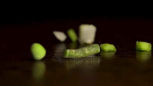 Verduras picadas. Rodajas de pimientos rojos y verdes, zanahorias, judías verdes, guisantes, cebolla, maíz cayendo sobre fondo negro. A cámara lenta. Las verduras picadas caen sobre fondo negro — Vídeo de stock