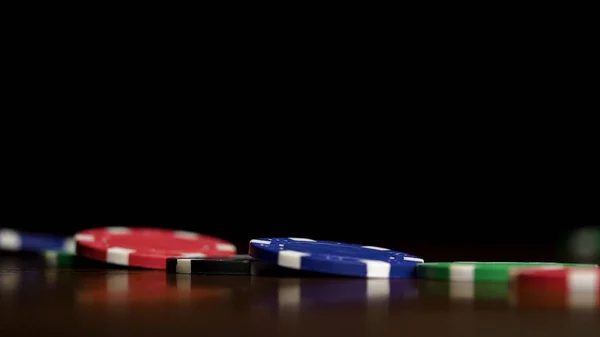 Poker fişleri üst üste siyah bir arka plan bir Domino etkisi üzerinde durmak. İskambil poker fişleri masanın üstünde, casino sembolü vardır — Stok fotoğraf