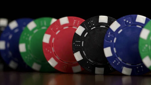 Żetony do pokera stoją w rzędzie na czarnym tle, efekt domina. Gry pokerowe żetony są na stole, symbol kasyno — Zdjęcie stockowe