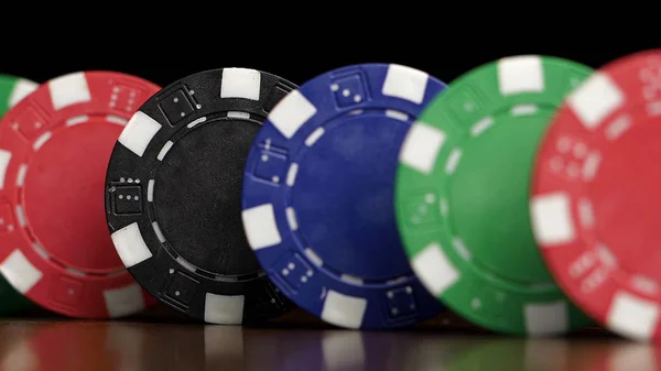 Poker fişleri üst üste siyah bir arka plan bir Domino etkisi üzerinde durmak. İskambil poker fişleri masanın üstünde, casino sembolü vardır — Stok fotoğraf