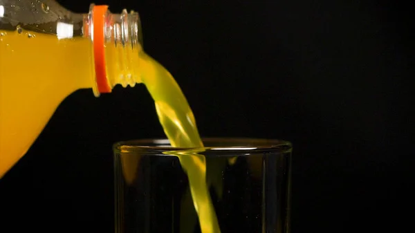 Orangefarbenes Getränk. Zeitlupe. kohlensäurehaltiges Orangengetränk wird in ein Glas gegossen. Orangensaft-Limo in Zeitlupe in Glas gießen, schwarzer Hintergrund — Stockfoto