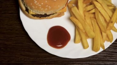 Ketçap ve hamburger ile kızarmış patates. Patates kızartması beyaz tabakta çizburger. Lezzetli lokanta