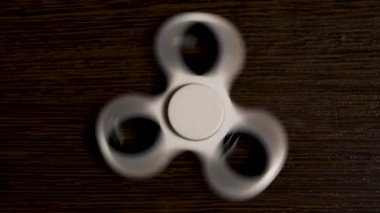 Beyaz spinner masaya dönüyor. Bir popüler beyaz oyuncak spinner ahşap bir masa üzerinde hareket iplik. Geliştirme, meditasyon, gevşeme