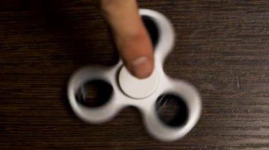 Beyaz spinner masaya dönüyor. Bir popüler beyaz oyuncak spinner ahşap bir masa üzerinde hareket iplik. Geliştirme, meditasyon, gevşeme