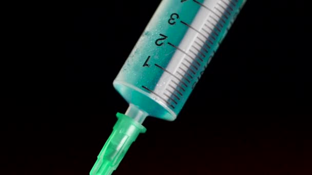 Vaccin rekening houdend een glazen injectiespuit uit een ampul op een zwarte achtergrond. Close-up. Spuit wordt getypt in turquoise vloeistof injectie van ziekte ernstige ziekten, het concept van de geneeskunde — Stockvideo