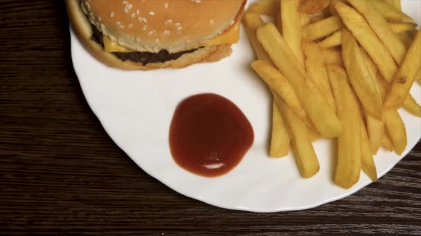 Hranolky s kečupem a hamburger. Cheeseburger s hranolky na bílé plotně. Vynikající rychlé občerstvení — Stock video