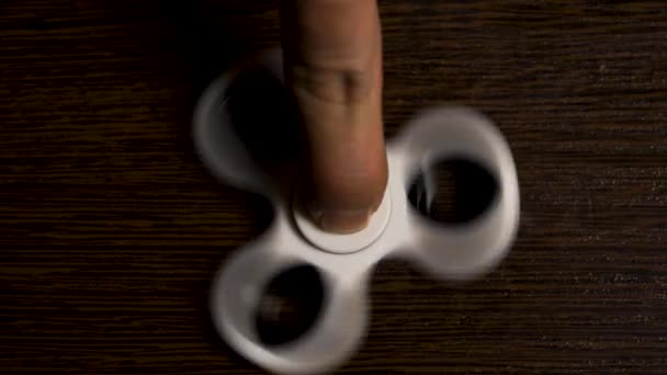 White spinner is spinning on the table. Spinning in motion of a popular white toy spinner on a wooden table. Developing, meditation, relaxation — Stock Video