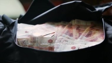 Rus para birimi cinsinden para dolu siyah bir çanta. Konu yolsuzluk ve Rusya'da mali suçlar cezasızlık kavramı. Rus parayı çantaya