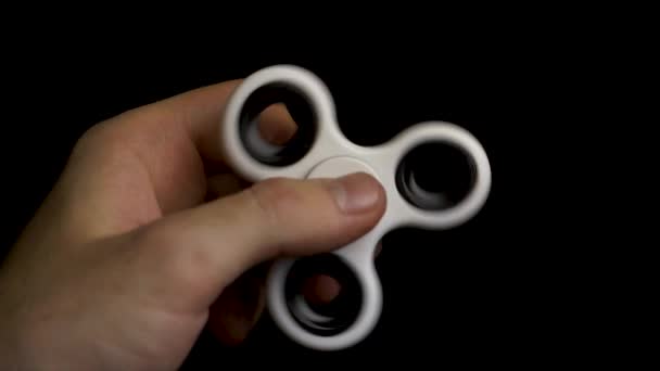 Fidget Spinner. Um fidget spinner branco numa mão de homem. Mão masculina segurando brinquedo popular fidget spinner. Fidget spinner stress aliviando brinquedo branco — Vídeo de Stock